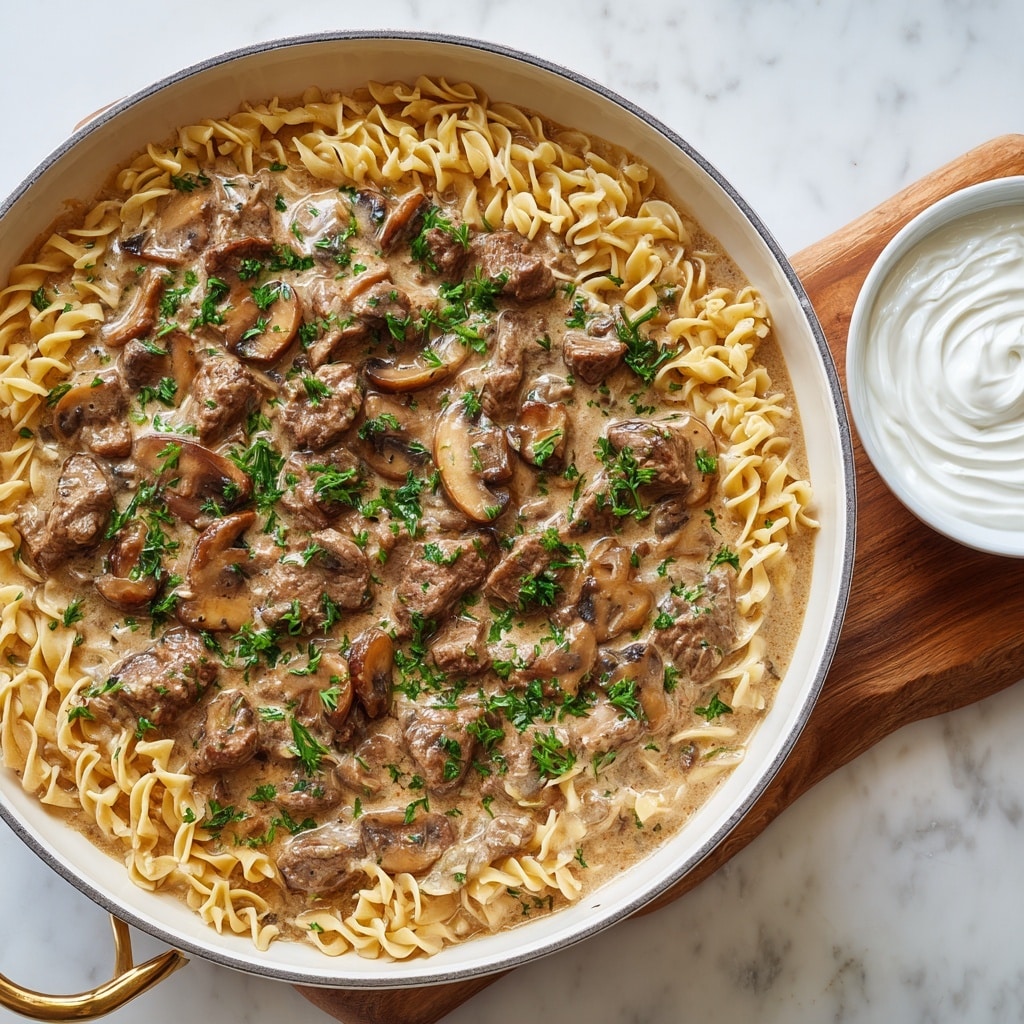 A white round pot filled with a creamy brown sauce containing several thick, dark brown strips of cooked meat and lighter brown mushroom slices. The sauce is smooth and glossy, coating the meat and mushrooms evenly. A black spoon is partially submerged on the right side, lifting some of the mixture. The pot rests on a white marbled surface with a folded white and gray striped cloth and two silver salt and pepper shakers in the top left corner. photo taken with an iphone --ar 4:5 --v 7
