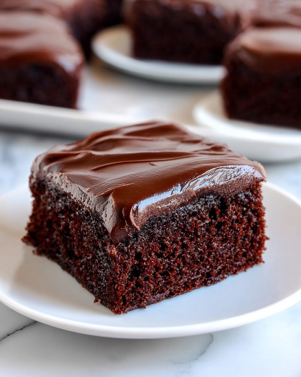 A close-up view of a single square piece of chocolate cake with two layers, placed on a white plate on a white marbled surface. The bottom layer is a moist, dark brown chocolate sponge with a soft and crumbly texture. The top layer is a thick, glossy, dark chocolate frosting spread evenly with visible smooth ridges. In the background, there are blurred multiple pieces of the same chocolate cake on white plates. photo taken with an iphone --ar 4:5 --v 7
