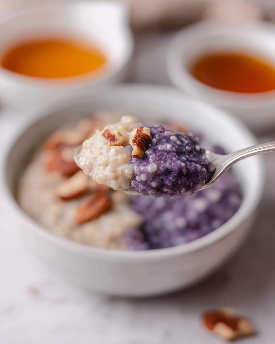 A white speckled bowl sits on a white marbled surface filled with a layered oatmeal dish; the first layer is creamy beige oatmeal on the left side, topped with fresh dark purple blueberries forming the second layer on the right side, mixed with some white creamy milk or yogurt that seeps between layers. Scattered over the blueberries are crunchy brown pecan nuts adding texture and contrast. In the background, there are two white bowls, one filled with more pecans and the other with a light amber liquid. A beige cloth with black stripes is partially visible at the bottom edge. Photo taken with an iphone --ar 4:5 --v 7