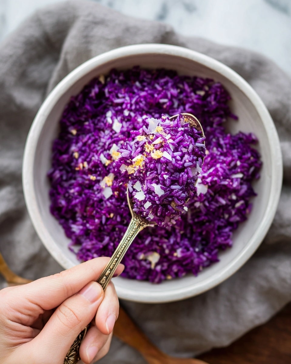 A close-up of white bowl filled with bright purple rice mixed with small white and yellow bits, creating a colorful texture. A spoon with an ornate handle is lifting a bite of the purple rice, showing the small grains and bits clearly. The woman's hand holding the spoon is visible at the bottom of the image. The bowl sits on a white marbled surface with a blurred gray cloth underneath. photo taken with an iphone --ar 4:5 --v 7