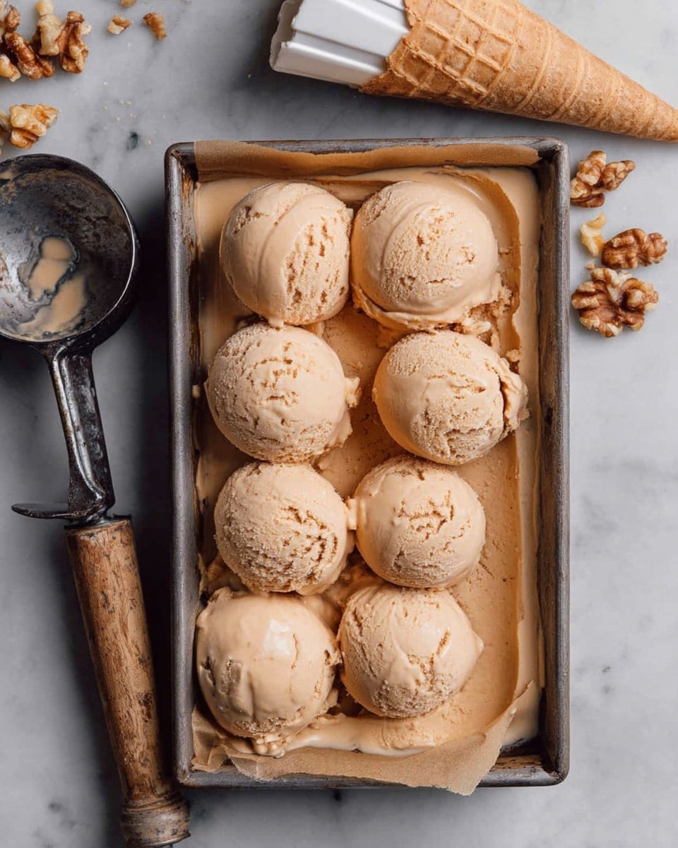 Seven scoops of light brown ice cream with a smooth, slightly cracked texture sit closely on brown parchment paper inside a metal tray. Three scoops form the top row, with two scoops in the middle and two scoops at the bottom, some melting with soft drips spreading underneath. A metal ice cream scoop with a worn wooden handle is placed on the left, holding one scoop. To the right above the tray, an empty white waffle cone rests on a white marbled surface. Crumbled walnut pieces are scattered near the cone. photo taken with an iphone --ar 4:5 --v 7