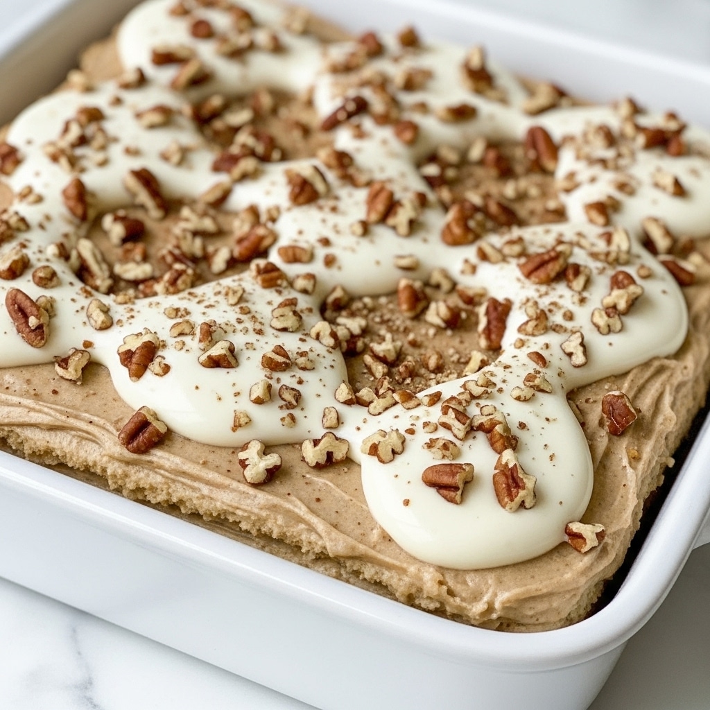 A white square baking dish holds a rich caramel-colored dessert with a glossy, sticky surface. The dish is filled with soft, rounded pieces that look soaked in a thick syrup, creating a slightly uneven, bumpy texture. On top, a generous layer of chopped pecans is spread evenly, showing small pieces and whole halves that add a crunchy texture contrast to the smooth syrup beneath. The background features a white marbled surface, giving a clean and elegant look. photo taken with an iphone --ar 4:5 --v 7