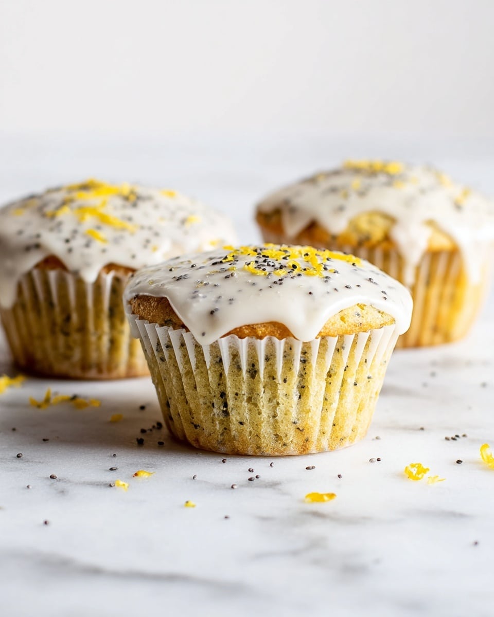 Three lemon poppy seed muffins are placed on a white marbled surface. Each muffin is in a white paper cup, with a pale yellow cake layer speckled with tiny black poppy seeds. The muffins are topped with a smooth, glossy white icing that drips slightly down the sides. Small black poppy seeds and fine yellow lemon zest are sprinkled on top of the icing and scattered around the base, adding texture and color contrast. The background is bright with soft focus, making the muffins the main focus. photo taken with an iphone --ar 4:5 --v 7