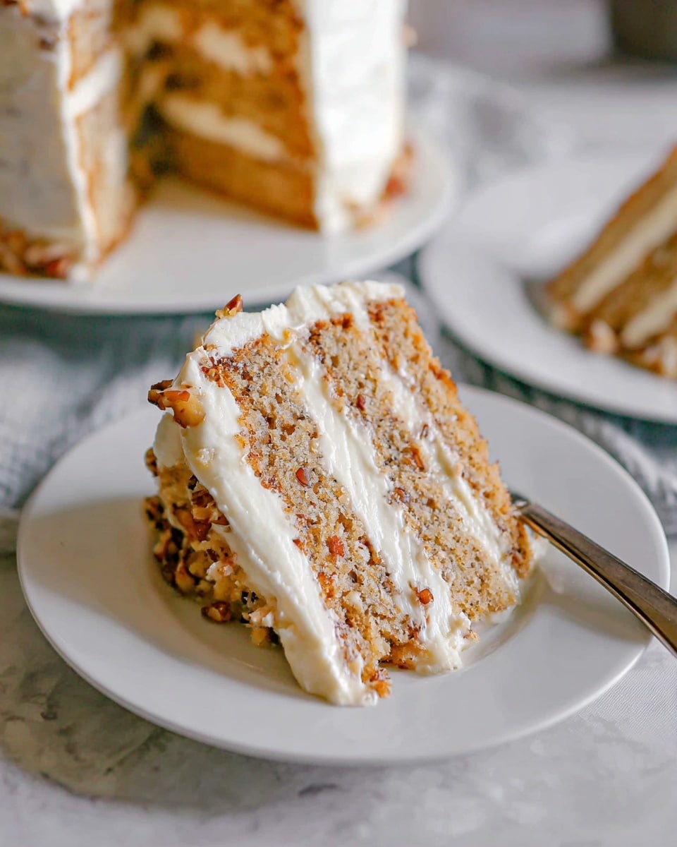 A slice of layered cake is placed on a white plate with a silver fork beside it. The cake has three visible layers of light brown sponge mixed with small nuts, separated by thick white cream frosting. The top of the slice is also covered with the same creamy white frosting, and some nuts are visible on the side. In the background, the rest of the cake with similar layers and frosting is seen on a white plate, all set on a white marbled surface. photo taken with an iphone --ar 4:5 --v 7