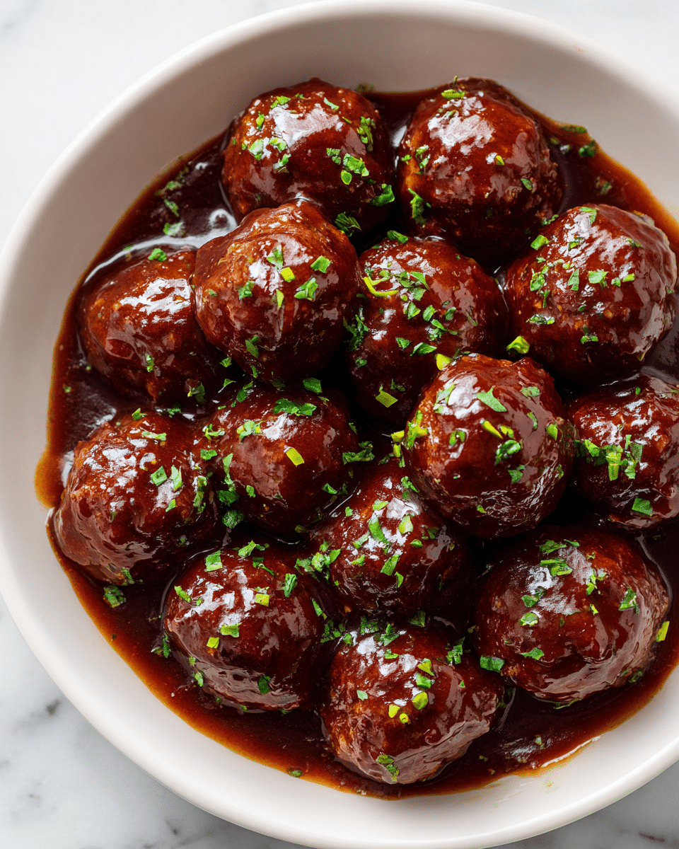 A white bowl filled with about fifteen glossy brown meatballs covered in a thick shiny sauce, each meatball is round and smooth with a rich glaze. The meatballs are garnished with small pieces of bright green chopped herbs scattered evenly on top. The bowl rests on a white marbled surface that adds a subtle, clean background to the warm colors of the dish. photo taken with an iphone --ar 4:5 --v 7