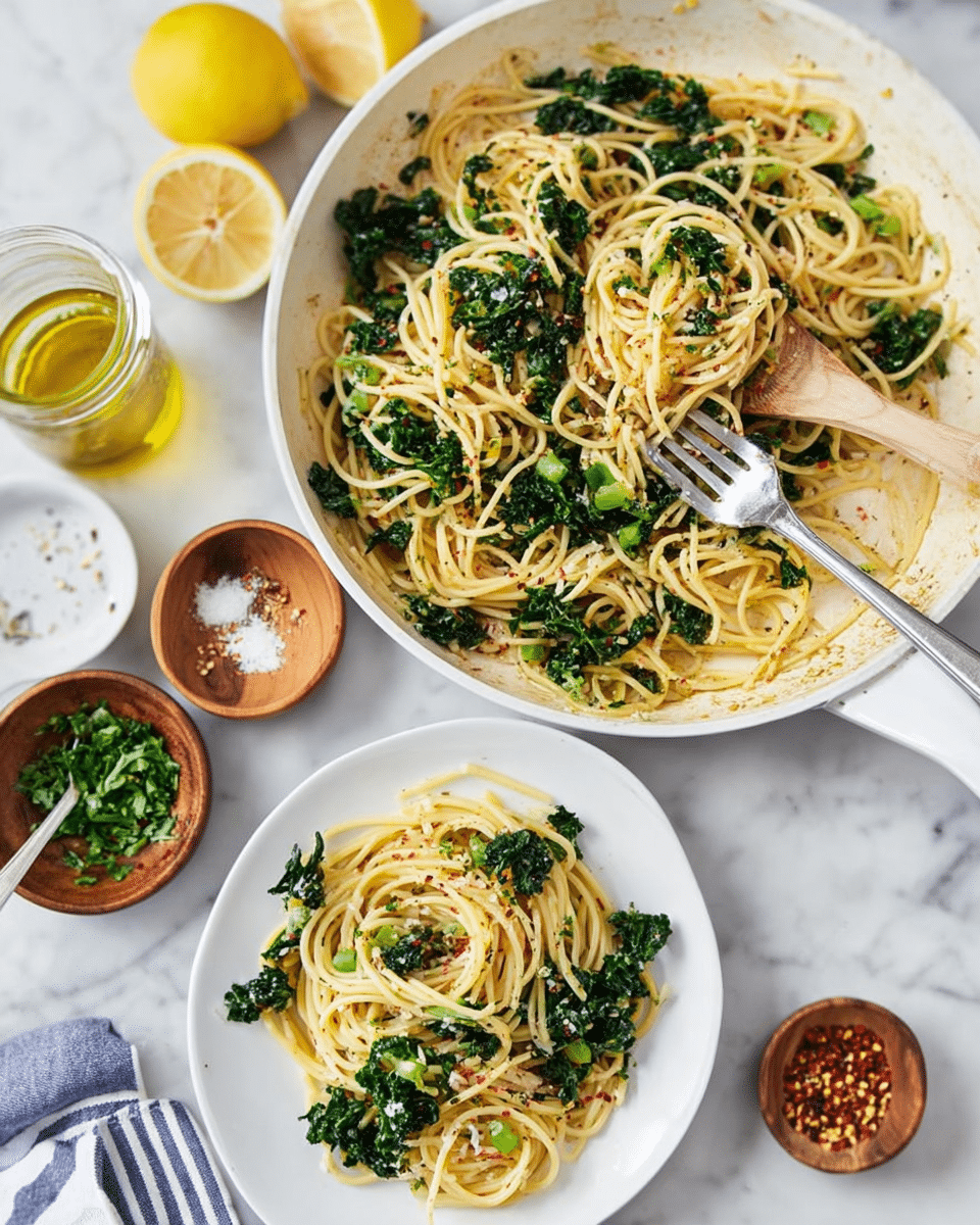 The image shows a white deep frying pan filled with cooked spaghetti mixed with dark green kale pieces spread evenly throughout the pasta, all resting on a white marbled surface. On the left side, there is a white plate with a serving of the spaghetti and kale mixture, with the pasta strands light yellow and slightly glossy, and scattered bits of seasoning visible on top. A fork is placed on the plate, partially inserted into the spaghetti. Nearby, there are two lemon halves, a small glass jar of oil, and three small wooden bowls containing green herbs, red chili flakes, and grated cheese. The colors are fresh and natural, reflecting a simple and clean presentation. Photo taken with an iphone --ar 4:5 --v 7