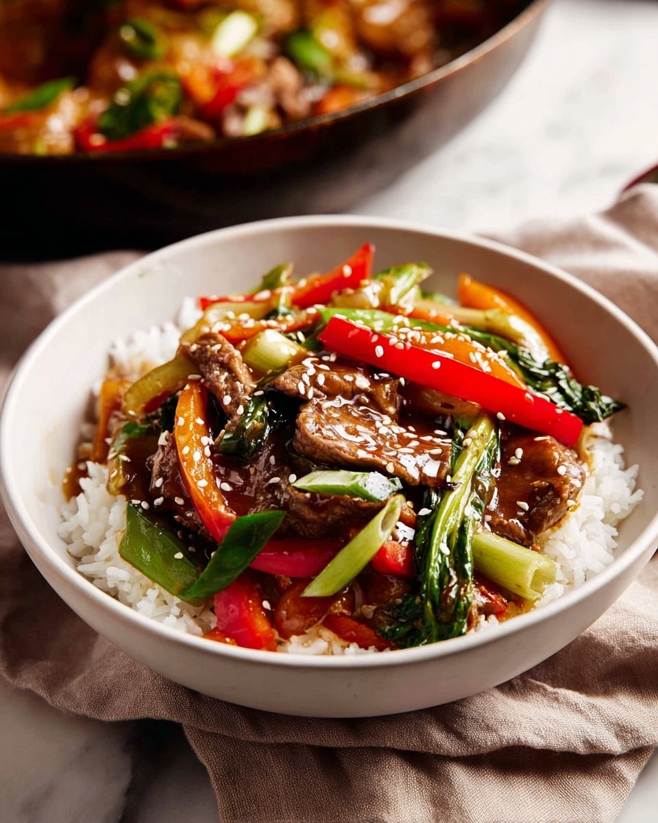 A white bowl filled with a base layer of white rice topped with a mix of stir-fried vegetables and beef slices coated in a glossy brown sauce. The vegetables include bright red and orange bell peppers, vibrant green bok choy and snap peas, and light green chunks of celery, all mixed evenly with tender beef pieces. The dish is sprinkled with white sesame seeds, adding texture and contrast. The bowl sits on a soft beige cloth on a white marbled surface. In the slightly blurred background, a pan with more stir-fried ingredients in warm tones is partially visible. photo taken with an iphone --ar 4:5 --v 7