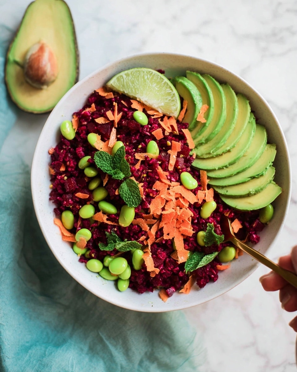 A white bowl filled with a colorful salad sits on a white marbled texture surface. The salad has a base layer of finely grated deep red beetroot mixed with small bright green edamame. Scattered on top are small orange carrot shreds and fresh green mint leaves. On one side of the bowl there are thin slices of pale green avocado fanned out neatly, while on the opposite side there is a halved avocado with a fresh mint leaf placed on it. A wedge of light green lime is placed near the edge of the bowl. A gold spoon partially rests inside the bowl with a woman's hand holding it. The colors are bright and fresh, with a soft natural light highlighting the textures and details of the salad ingredients. Photo taken with an iphone --ar 4:5 --v 7