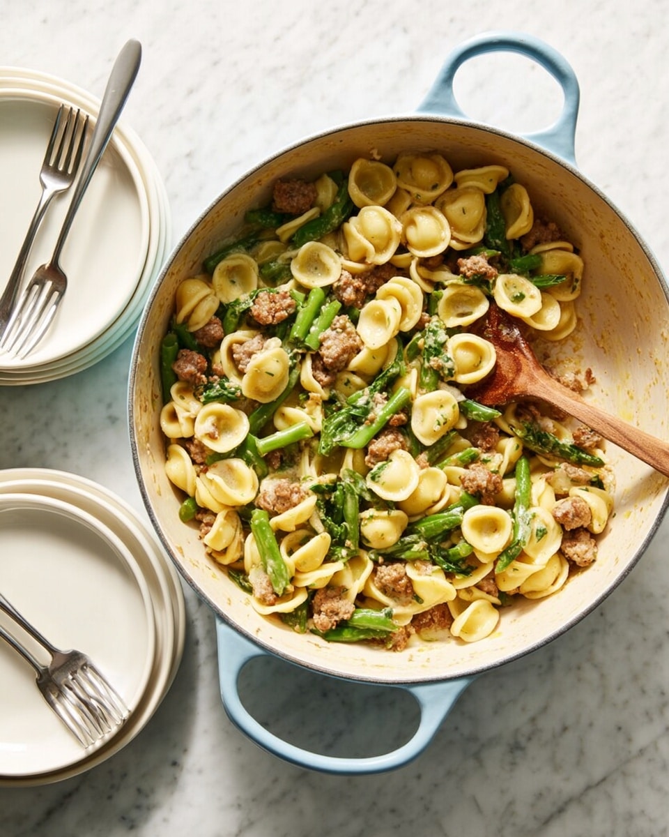 A large light blue pot with two handles holds a cooked dish of orecchiette pasta, mixed with green beans cut into small pieces, and browned sausage chunks. The pasta is pale yellow with a soft texture, scattered uniformly throughout. The green beans add bright green color and a fresh, slightly crunchy contrast, while the sausage pieces are small, browned, and slightly crisp on the edges. A wooden spoon is resting inside the pot on the right side, with some sauce residue on it. Next to the pot is a set of two stacked white plates with two forks resting on top, placed on a white marbled surface. photo taken with an iphone --ar 4:5 --v 7
