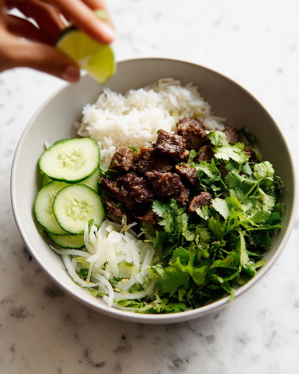 A bowl with three main layers: at the bottom, there is a layer of white rice that looks soft and fluffy; on one side, thinly sliced cucumbers and onions are mixed together, showing a light green and white color with a fresh, crunchy texture; on top, small pieces of dark brown grilled meat sit in the center, sprinkled with fresh green cilantro leaves. A woman's hand is seen squeezing a fresh lime above the bowl. The bowl itself is white, set on a white marbled surface. photo taken with an iphone --ar 4:5 --v 7
