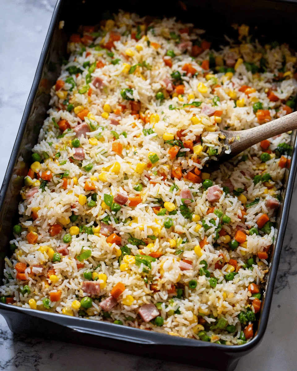 In the image, a large black rectangular pan holds a colorful dish of fried rice mixed with small diced carrots, green peas, yellow corn, green onions, and small pieces of pink ham. The rice is white with a slightly golden color from cooking, showing a soft texture that is mixed evenly with the colorful vegetables and meat. The ingredients are spread clearly, creating a bright and inviting mix of orange, green, yellow, and pink throughout the white rice. A spoon with a wooden handle is partially visible stirring the rice near the front of the pan. The pan sits on a surface with a white marbled texture. photo taken with an iphone --ar 4:5 --v 7