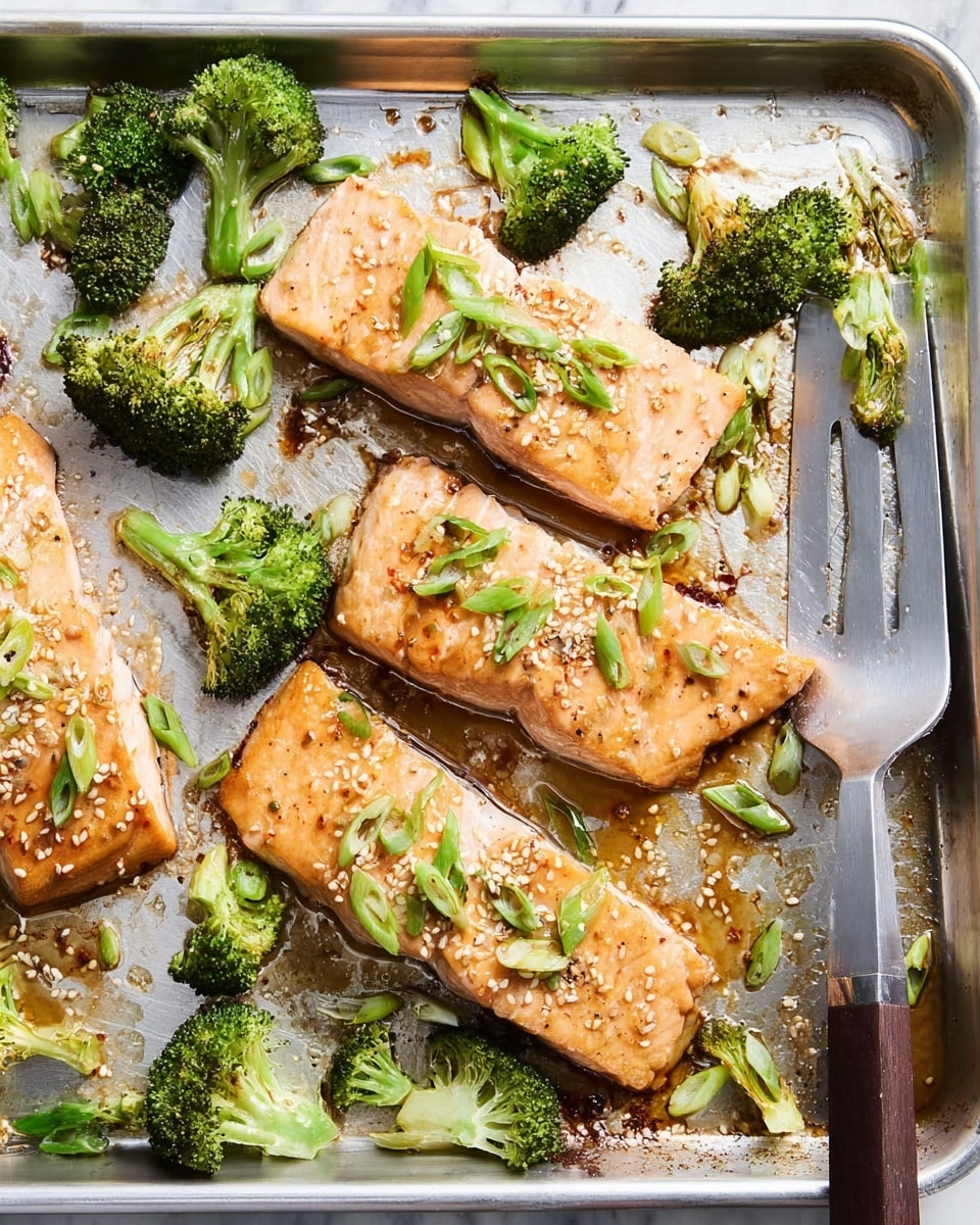 Four pieces of cooked salmon fillets with a light golden-brown sear are placed on a silver baking tray, each topped with small slices of green spring onions and white sesame seeds. Bright green broccoli florets are scattered around the salmon, some with slightly crisped edges, adding texture and color contrast. A metal spatula with a dark brown handle is resting on the tray's edge, partially under one salmon piece. The tray surface shows some brown roasted marks and bits of seasoning. The whole scene is set on a white marbled texture. photo taken with an iphone --ar 4:5 --v 7