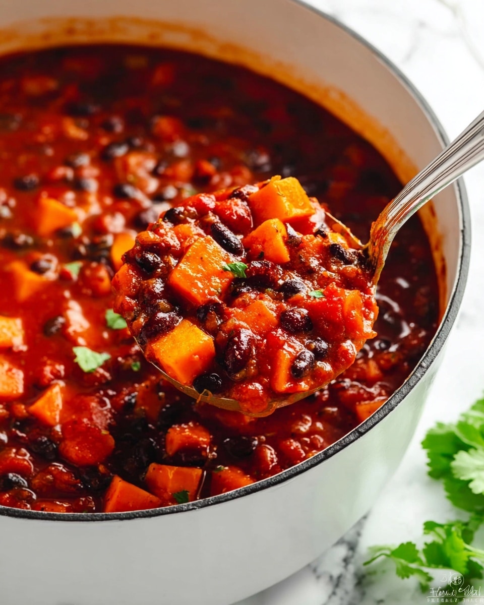 A close-up view of a white pot filled with chunky stew showing three main layers: the base layer is deep red thick sauce with a glossy texture, the middle layer has bright orange cubed sweet potatoes and black beans scattered evenly, and the top layer features tomato pieces and small bits of spices mixed throughout. A silver ladle scoops the stew, lifting a generous portion that clearly shows all the layers mixed, while the pot rests on a white marbled surface with some green leafy garnish blurred in the background. Photo taken with an iphone --ar 4:5 --v 7