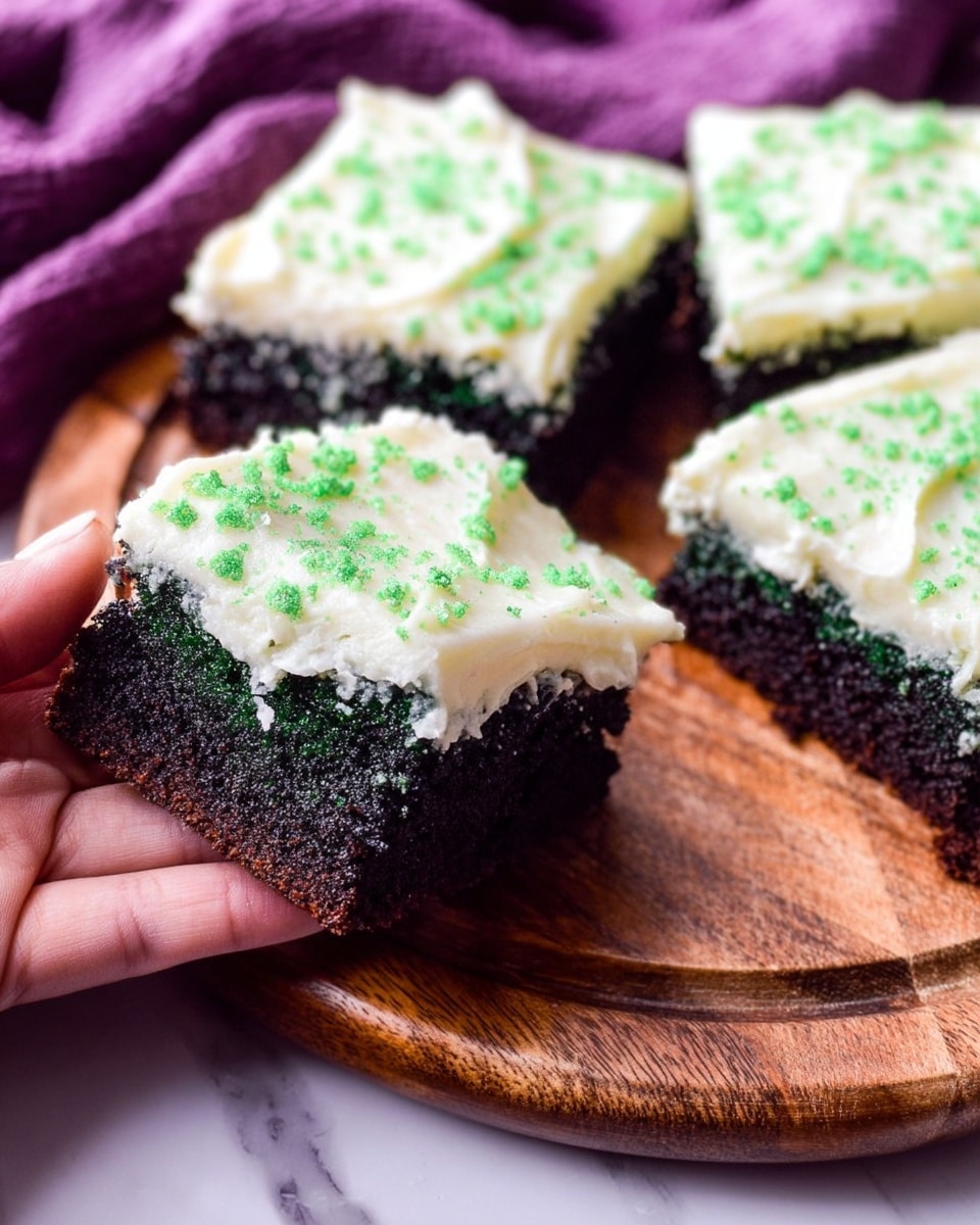 The image shows close-up pieces of dark green cake with white creamy frosting on top, with small green sugar sprinkles evenly spread on the frosting. Each cake piece appears soft and textured, with one piece held by a woman's hand on the left side, showing the thick dark green cake base and the smooth white frosting layer on top. The cakes are arranged on a round wooden board with a visible grain texture, placed on a white marbled surface with a purple cloth in the background. The frosting layer looks fluffy and inviting, covering the entire top of each cake piece. photo taken with an iphone --ar 4:5 --v 7