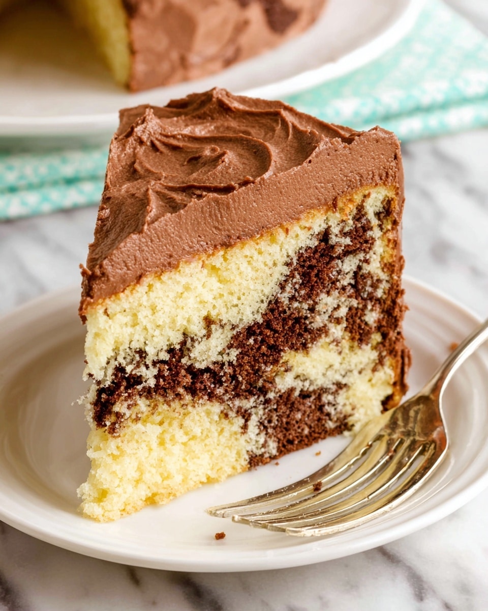 A slice of two-layer marble cake sits on a white plate with a silver fork next to it, all on a white marbled surface. The bottom layer is a light yellow cake with soft texture, followed by a thick middle layer of smooth chocolate frosting with some specks of cake mixed in. The top cake layer is marbled with light yellow and dark brown spots, and the whole slice is covered with a thick, creamy layer of chocolate frosting that is lightly textured with swirls on top. Photo taken with an iphone --ar 4:5 --v 7