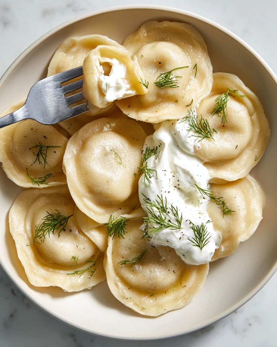 A white plate holds eight round dumplings with thick, pale beige dough and a smooth, slightly shiny texture. The dumplings are arranged closely together, with a dollop of white sour cream on the right side, topped with small green dill leaves. One dumpling is lifted by a silver fork from the top left corner, showing its hollow underside and a bit of sour cream on its edge. The dumplings and sour cream are garnished with more scattered dill sprigs, adding a touch of green to the creamy dish. The whole scene sits on a white marbled texture. photo taken with an iphone --ar 4:5 --v 7