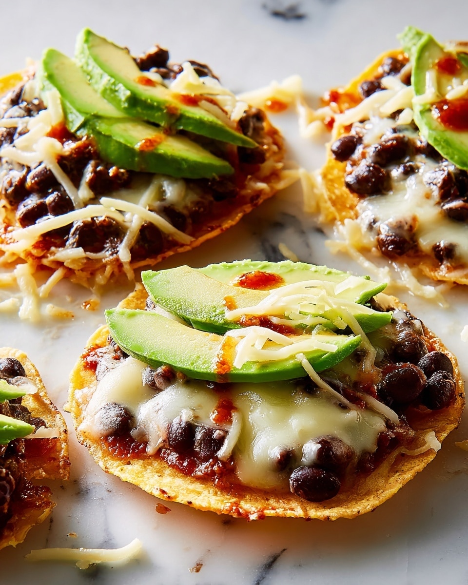 The image shows small round tostadas with three clear layers. The base layer is a golden brown crispy corn tortilla, slightly rough and crunchy. The second layer is melted white cheese, spread evenly over the tortilla, soft and gooey in texture with some cheese strands visible. On top of the cheese sits a layer of black beans, dark and shiny, scattered but thick enough to cover most of the cheese. The top layer features slices of fresh avocado, bright green and creamy, arranged in a fan shape. There are a few spots of red sauce drizzled on the avocado and cheese layers. The tostadas are on a white marbled surface with some melted cheese and beans scattered around. photo taken with an iphone --ar 4:5 --v 7