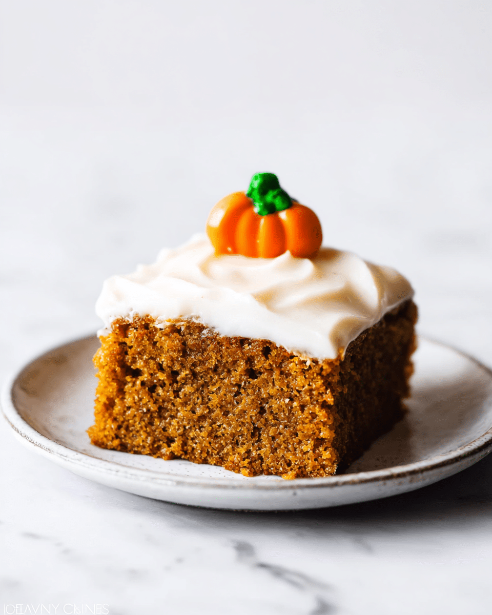 A single square piece of moist, brown pumpkin cake sits on a white plate. The cake has a light, creamy white frosting layer evenly spread on top, slightly smooth but with gentle waves. On the center of the frosting, a small pumpkin-shaped decoration with an orange body and green leaf detail adds a festive touch. The background shows a clean white marbled texture, highlighting the cake slice's rich texture and soft crumb. photo taken with an iphone --ar 4:5 --v 7