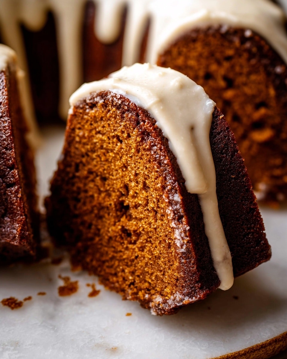 A close-up view of a bundt cake with a rich brown color, sliced to show its moist and dense crumb texture. The cake has one main layer with a thick, creamy white icing generously drizzled over the top, slightly dripping down the sides. The slice in focus is leaning forward, resting on a white plate with some icing pooled underneath. The background is a white marbled texture, softly blurred to keep all attention on the cake and its glossy icing. photo taken with an iphone --ar 4:5 --v 7