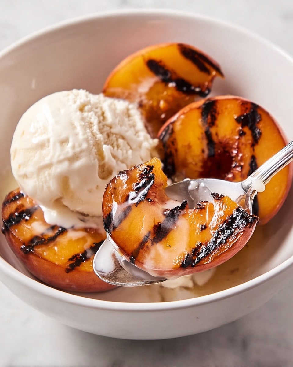 The image shows a white bowl filled with three grilled peach slices with dark, crisp grill marks on their shiny orange surface. On top of the peaches, there is a large scoop of creamy white vanilla ice cream starting to melt. A spoon lifting one peach slice covered in melting ice cream is visible in the front. The bowl sits on a smooth white marbled surface. photo taken with an iphone --ar 4:5 --v 7