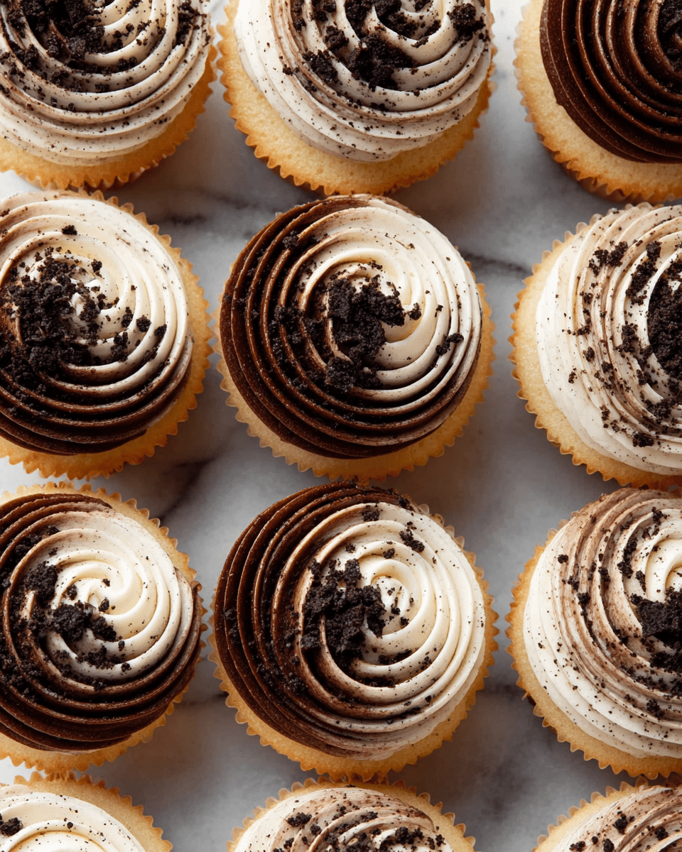 The image shows a close-up of a cupcake with a bite taken out of it, revealing a light beige cake with dark cookie crumbs inside. On top of the cupcake, there is a swirl of two icing layers: one side is white and creamy, and the other side is smooth, rich chocolate brown. Small crushed cookie pieces are sprinkled on the icing. The cupcake is placed on a white speckled plate with the paper wrapper peeled down. In the blurred background, several similar cupcakes with the same two-tone icing swirl can be seen on a white marbled surface. photo taken with an iphone --ar 4:5 --v 7