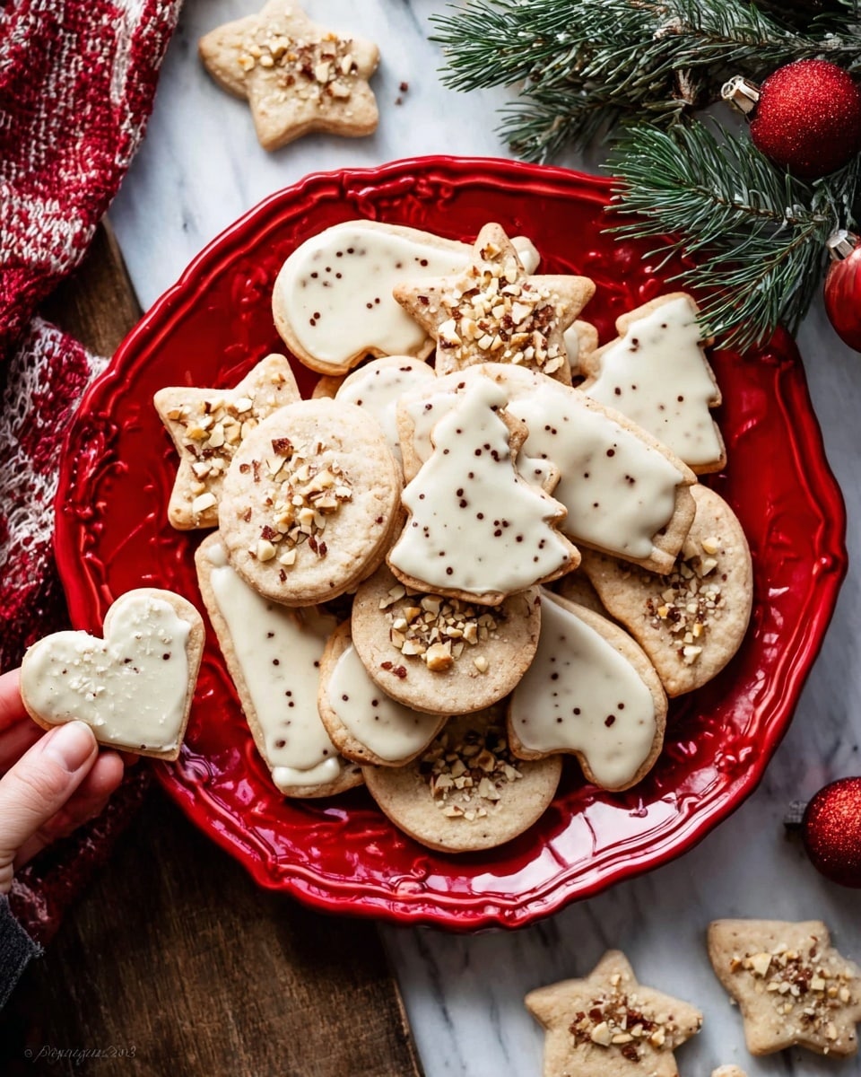 A red plate filled with various Christmas-shaped cookies, including hearts, trees, mittens, and stars, all topped with a smooth white icing layer and sprinkled with small chopped nuts. Some cookies are stacked, showing a light beige base with small chocolate specks. Around the plate, several undecorated cookies of the same shapes are scattered on a white marbled surface, adding a festive feeling with green pine sprigs and red baubles nearby. A woman's hand is holding a partially eaten heart-shaped cookie on the left side. Photo taken with an iphone --ar 4:5 --v 7