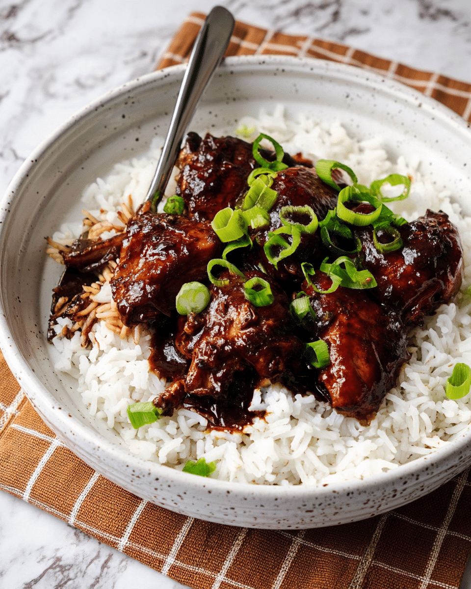 The dish is served in a large white speckled bowl with a base layer of fluffy white rice spread evenly across the bottom. On top of the rice, there are several pieces of dark brown glazed chicken coated in a shiny sauce, placed more toward the center. The chicken looks tender and moist, with some pieces partially cut to show texture inside. Bright green chopped scallions are scattered on top of the chicken, adding a fresh pop of color. A silver fork rests on the left edge of the bowl, slightly catching some rice grains and sauce. The bowl is set on a brown checkered cloth with a white marbled surface underneath. Photo taken with an iphone --ar 4:5 --v 7