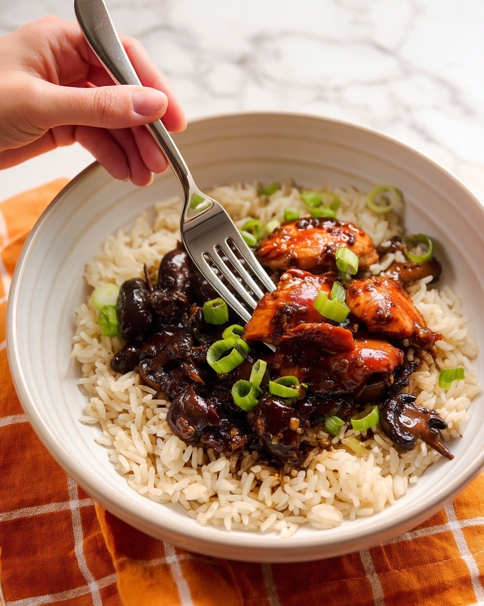 A close-up view of a white bowl filled with a base layer of light, fluffy cooked rice that has a slightly separated grain texture. On top of the rice is a layer of dark glossy cooked mushrooms and sauce covering tender pieces of reddish-brown chicken with a moist texture. Bright green chopped scallions are scattered over the chicken and sauce, adding a fresh contrast. A woman's hand holding a shiny silver fork is about to pick up a piece of the mushroom and chicken mixture. The bowl sits on a white marbled surface with an orange checkered cloth partially visible underneath. Photo taken with an iphone --ar 4:5 --v 7